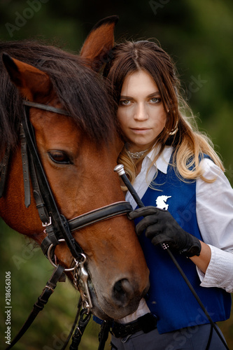 Face of young woman rider equestrian and brown horse touch each other, concept friends.