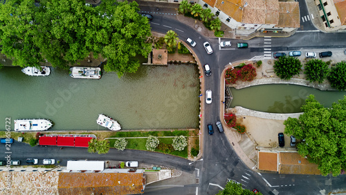 Aerial top view of boats and lock in Canal du Midi, road and bridge from above, Southern France
