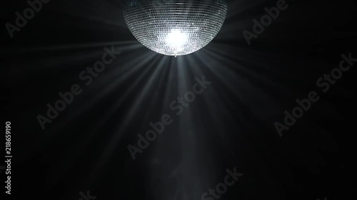 Silver mirror disco ball rotating in black space photo