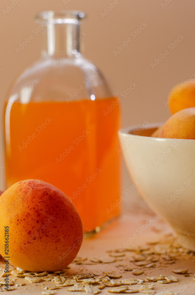 Lots of apricots on a white plate and glass of apricot juice on a white table strewn with oatmeal. Lots of apricots on a white plate and glass of apricot juice on a white table strewn with oatmeal.