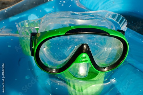 green diving mask for kids on blue sea ​​mattress on sunny day at the beach close up  © emiphoto111