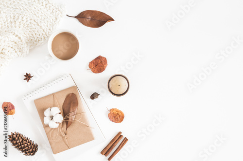 Autumn or winter composition. Cup of coffee, gift, dried autumn leaves, beige sweater on white background. Flat lay, top view, copy space