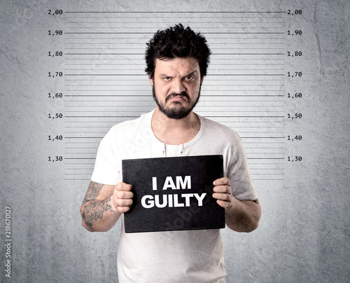 Caugth offender in front of a wall with table in his hand. photo