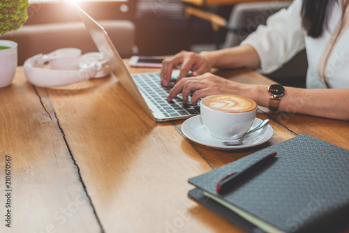 Close up of woman typing keyboard on laptop in coffee shop. People and technology concept. Freelance and Lifestyle theme. Entrepreneur and working outside office theme.