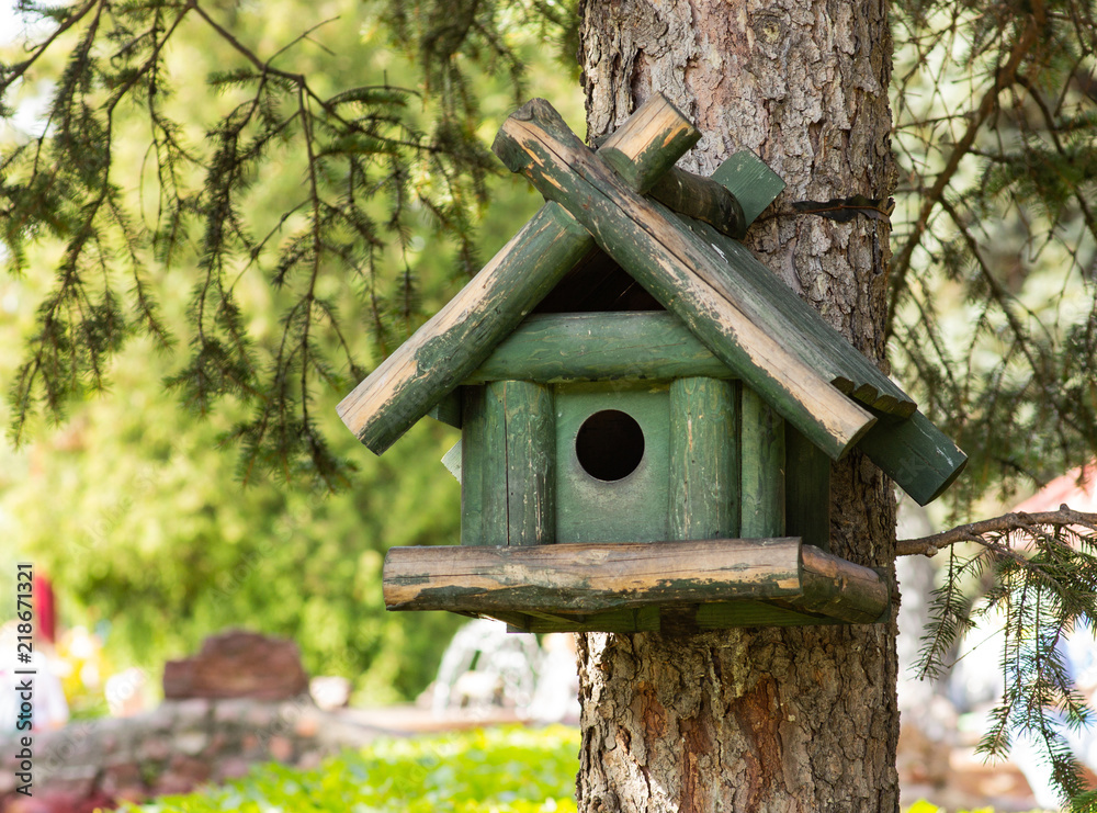 A green birdhouse on a tree, the background is blurred A green birdhouse on a tree, the background is blurred