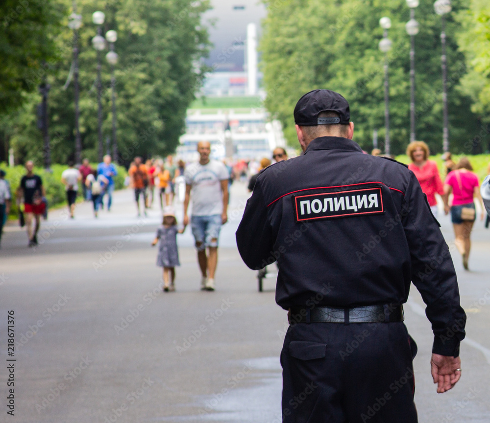 St. Petersburg, Russia - August 4, 2018: A policeman patrols the park near the football stadium. St. Petersburg, Russia - August 4, 2018: A policeman patrols the park near the football stadium.