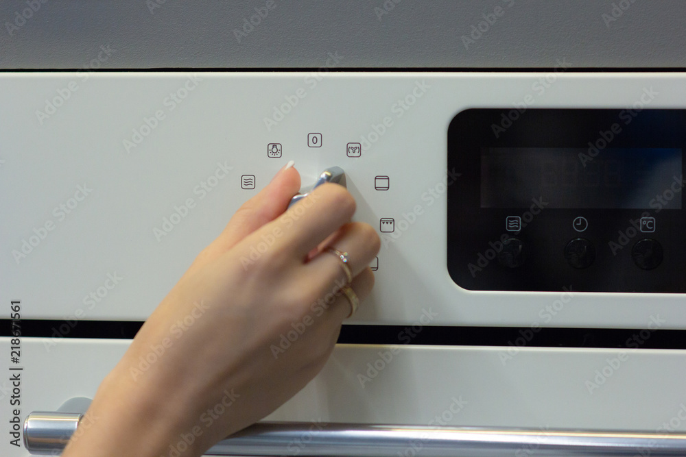 The girl sets the cooking mode in the oven The girl sets the cooking mode in the oven