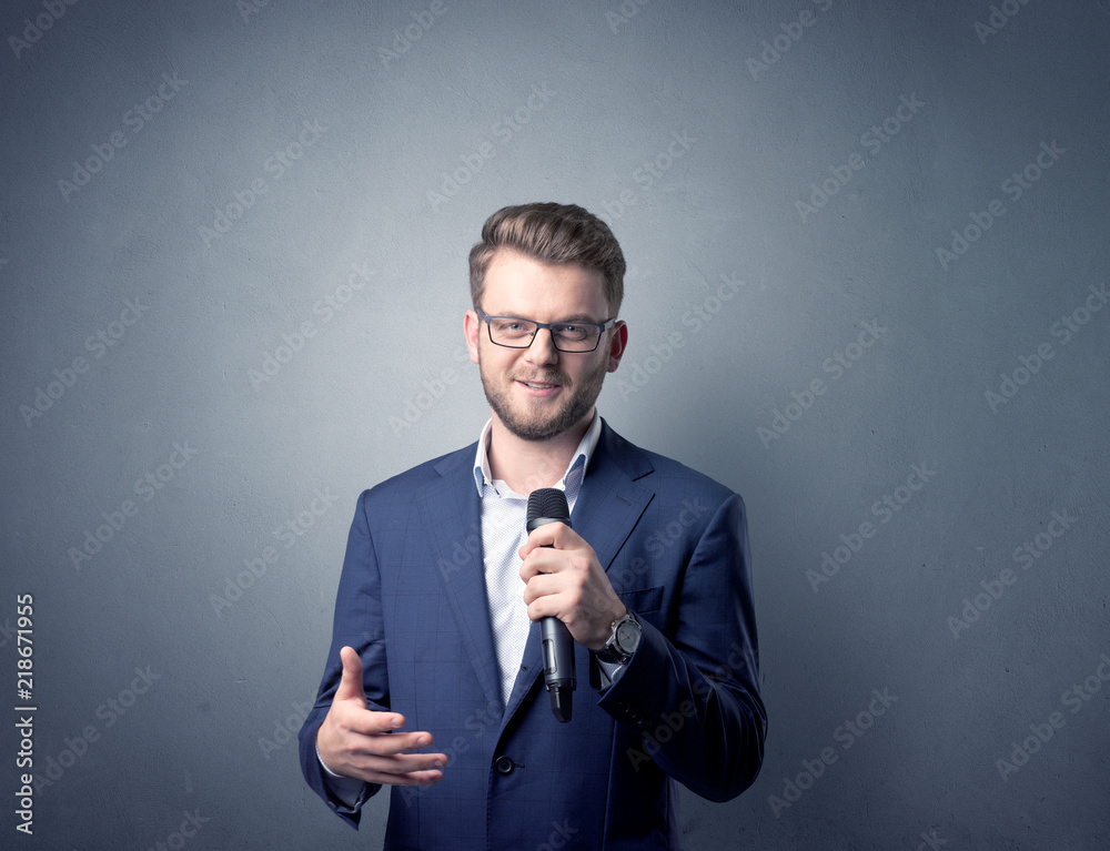 Businessman speaking into microphone with blue background Businessman speaking into microphone with blue background