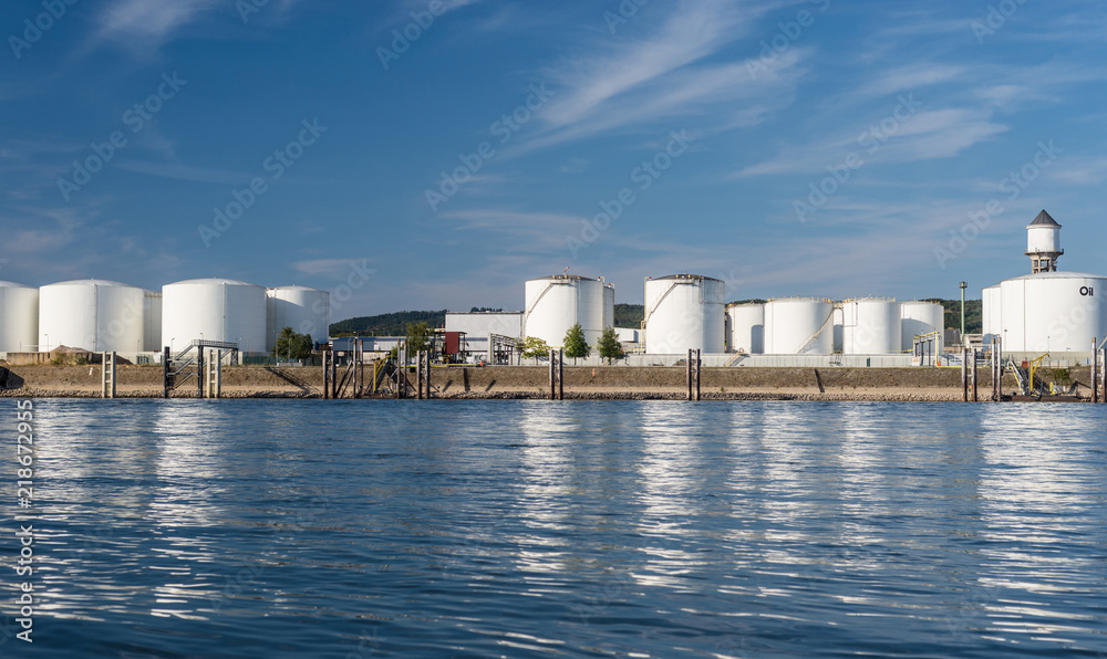 Storage silos,fuel depot of petroleum and gasoline on the banks of the river in western Germany on a beautiful blue sky with clouds. Storage silos,fuel depot of petroleum and gasoline on the banks of the river in western Germany on a beautiful blue sky with clouds.
