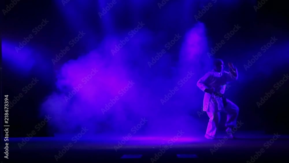 A karate master with a black belt on a black background is engaged in karate A karate master with a black belt on a black background is engaged in karate
