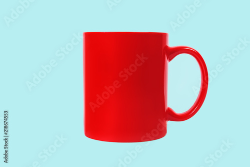 Red ceramic coffee mug isolated on blue background. Front view