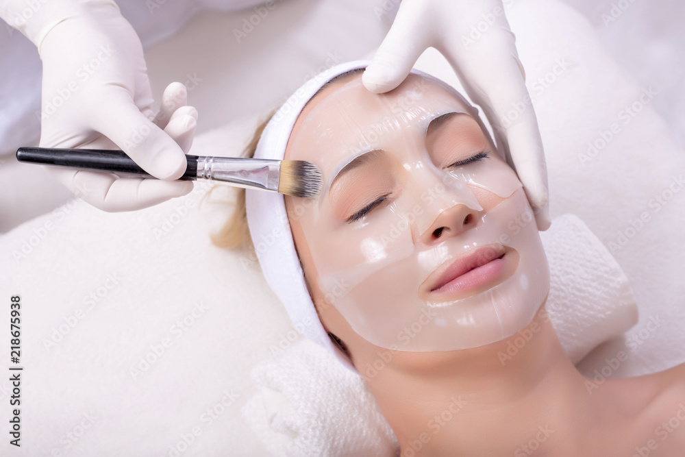 Portrait of beautiful woman getting beauty skin mask treatment on her face with brush