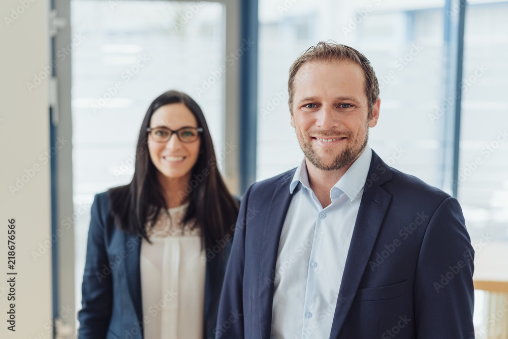 Cheerful businessman with woman in background Cheerful businessman with woman in background