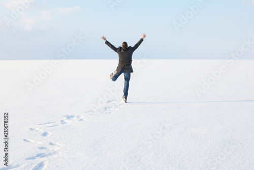 man standing on the shore of a frozen sea downshifting way relaxes on a winter seascape