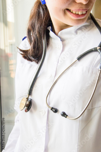 Medical concept of female doctor in white coat with phonendoscope, no face, close up. Smiling medical doctor or nurse