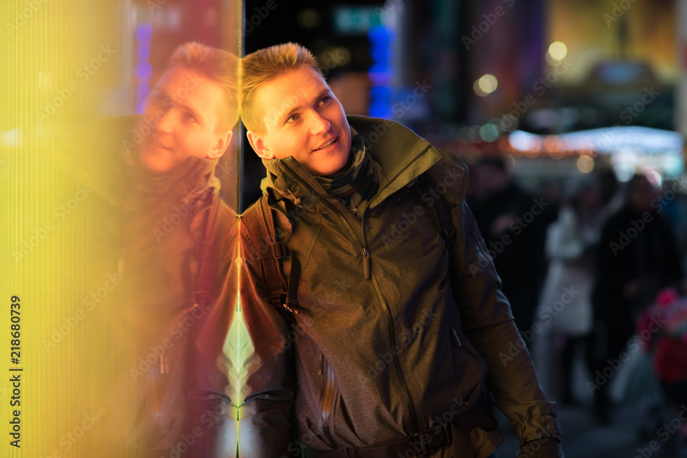 Stylish young man with his reflection on background with blurred lights of the city at night Stylish young man with his reflection on background with blurred lights of the city at night