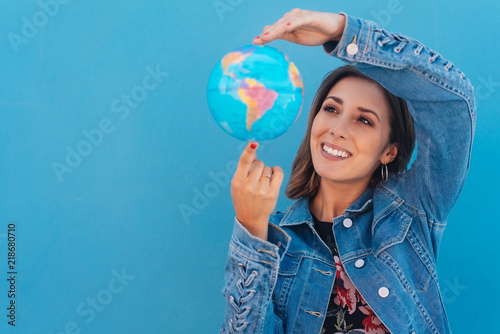 Happy young woman spinning a globe in her hands #218680710