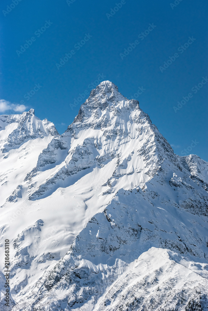 Mt. Belalakaya summit against clear blue sky in winter sunny day. Dombay ski resort, Western Caucasus, Russia.