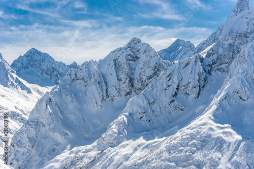 Snow covered winter Caucasian mountains in sunny day. Dombai ski resort, Karachai-Cherkess, Russia.