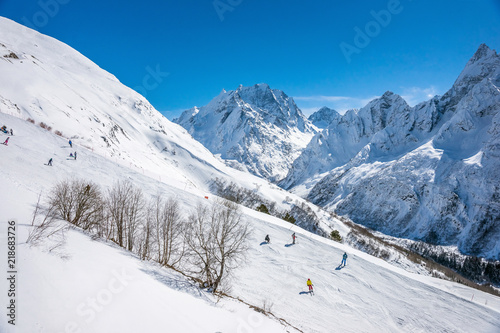 Ski slope with Mt. Dombay-Ulgen on the horizon in winter sunny day. Dombai ski resort, Western Caucasus, Russia. © Anna