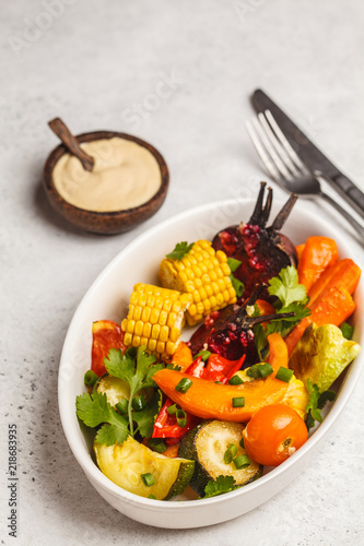 Baked vegetables  pumpkin  beets  carrots  peppers  zucchini and corn in white dish  white background.