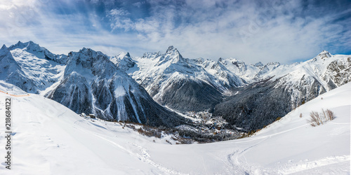 Panoramic view of the ski slope with the mountains Belalakaya, Sofrudzhu and Sulakhat on the horizon in winter day. Dombai ski resort, Western Caucasus, Karachai-Cherkess, Russia. photo