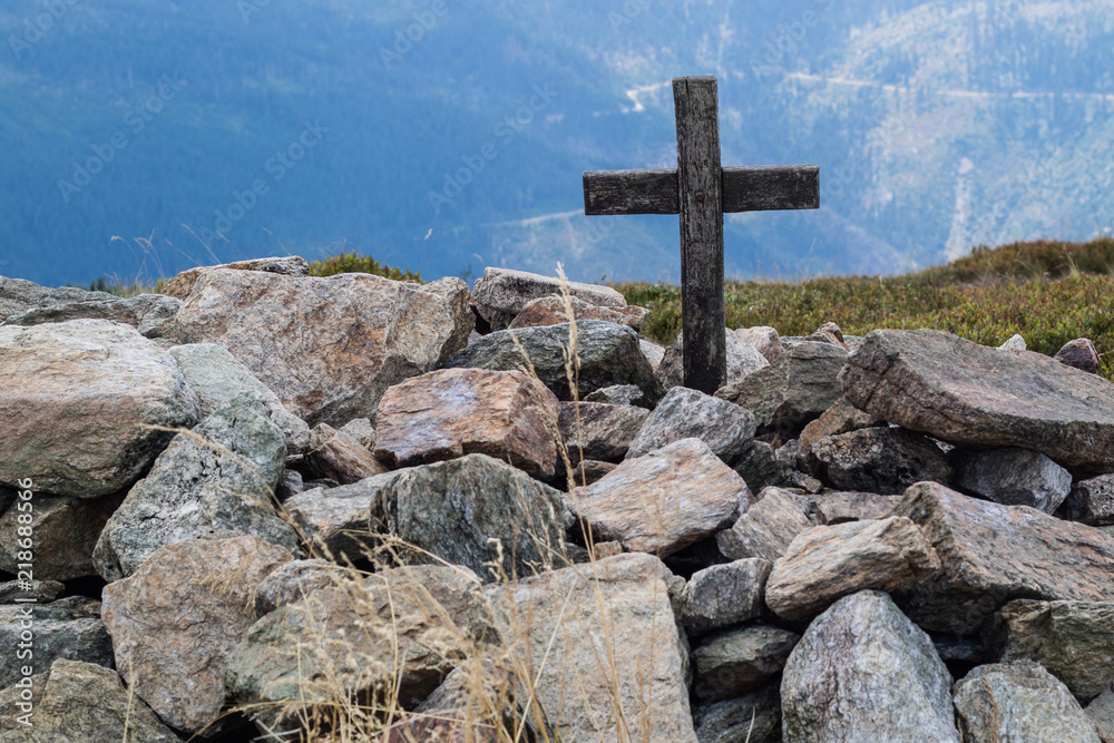 Cross on the top of a mountain in central europe. A wooden sign of Christianity lined with stones.