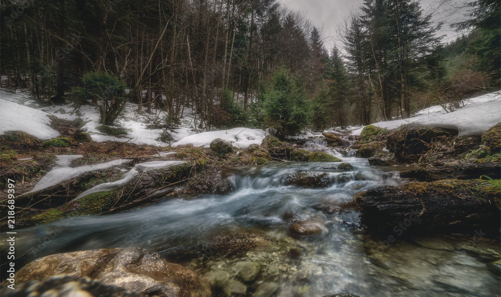 The flow of the river between the rocks. Winter stream of a mountain river The flow of the river between the rocks. Winter stream of a mountain river