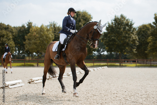 Reiterin galoppiert mit ihrem Pferd in einer Dressurprüfung auf einem Turnier auf Kandare