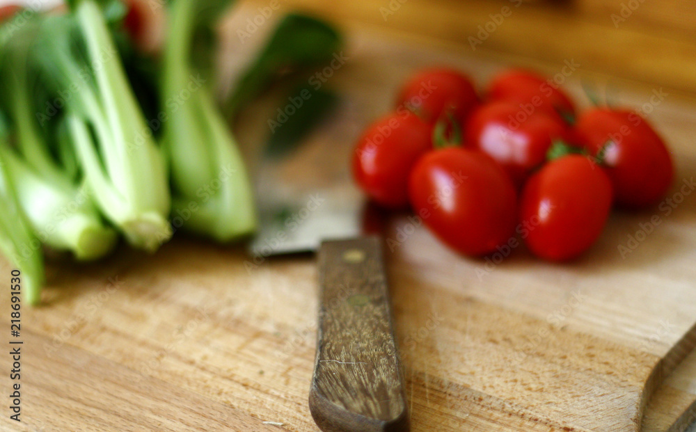 Fresh baby pak choi and tomatoes on wooden chopping board 1 Fresh baby pak choi and tomatoes on wooden chopping board 1