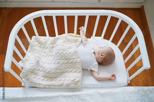 Baby girl sleeping in co-sleeper crib photo