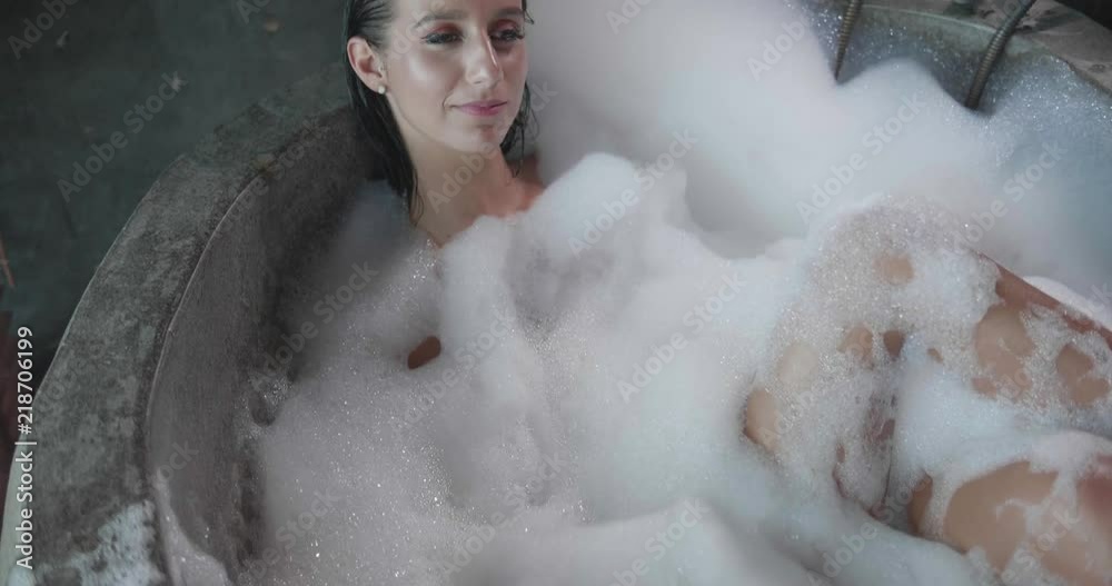 Attractive girl in the bath blowing foam and smiling Attractive girl in the bath blowing foam and smiling