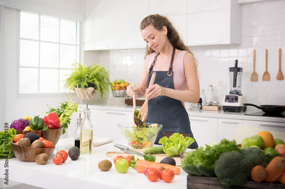 Healthy young woman in a kitchen preparing vegetables for healthy meal and salad Healthy young woman in a kitchen preparing vegetables for healthy meal and salad