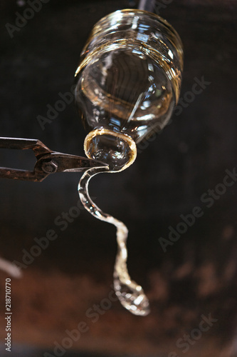 A glassmaker cuts excess glass from a decanter