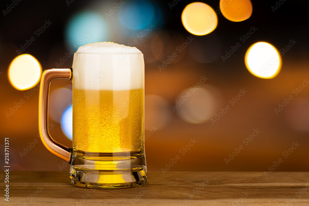 Glass of beer on wood table in pub with bokeh light night background , drinking alcohol celebration concept design with copy space