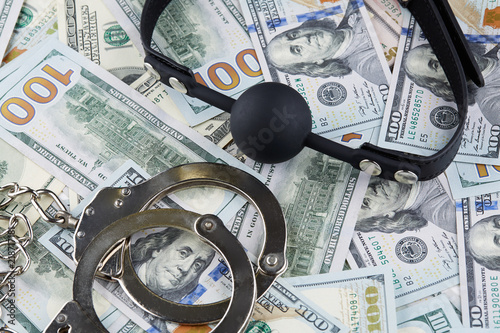 Black gag and handcuffs on american dollars banknotes