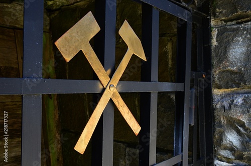 Gold coloured crossed hammers as symbol on entrance fence on opal mine.