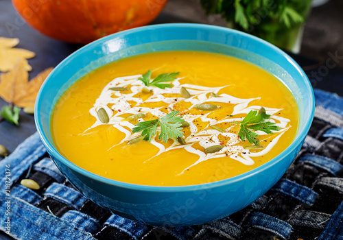 Pumpkin soup in a bowl served with parsley and pumpkin seeds. Vegan soup. Thanksgiving day food. Halloween meal.
