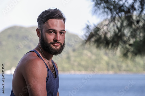 Handsome young man near sea  pine branch and mountain background in Turkey