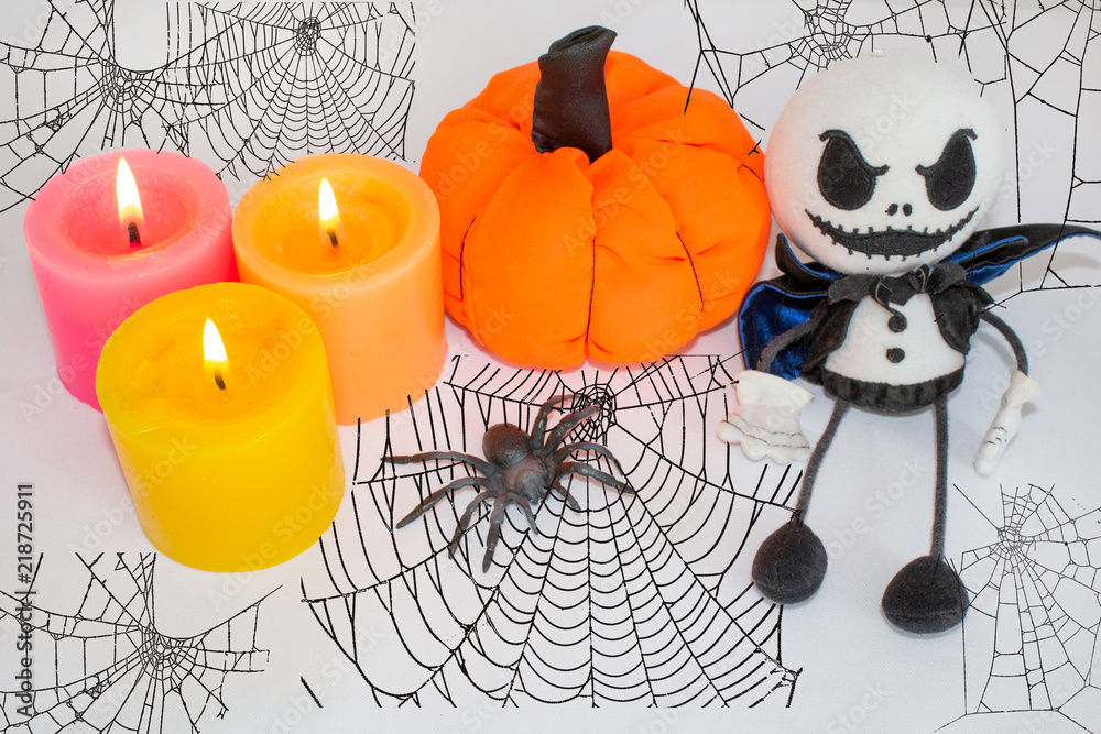 Postcard for Halloween, candles with a pumpkin, a spider and a ghost doll. Against the background of cobwebs. Postcard for Halloween, candles with a pumpkin, a spider and a ghost doll. Against the background of cobwebs.