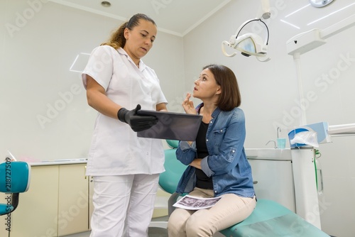 Dentist showing a patient her teeth x-ray. Healthcare, medical and dentistry concept