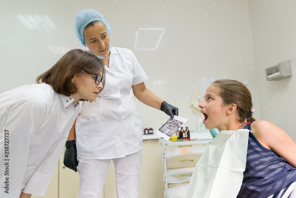 Fototapeta premium Doctors orthodontists look at the x-ray, child patient in armchair. Healthcare, medical and dentistry concept