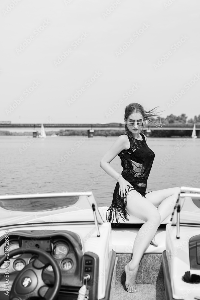 Image of young amazing red hair attractive girl in sunglasses wearing black T-shirt with fringe on the yacht. Carefree time on yacht. Beautiful woman on her private yacht 