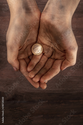 Obraz na plátně Dirty child's hands with one euro coin, poverty symbol, with copy space