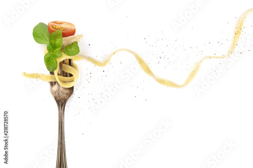 Italian pasta. Overhead photo of vintage fork with pappardelle, basil, cheese, and tomato, on white background