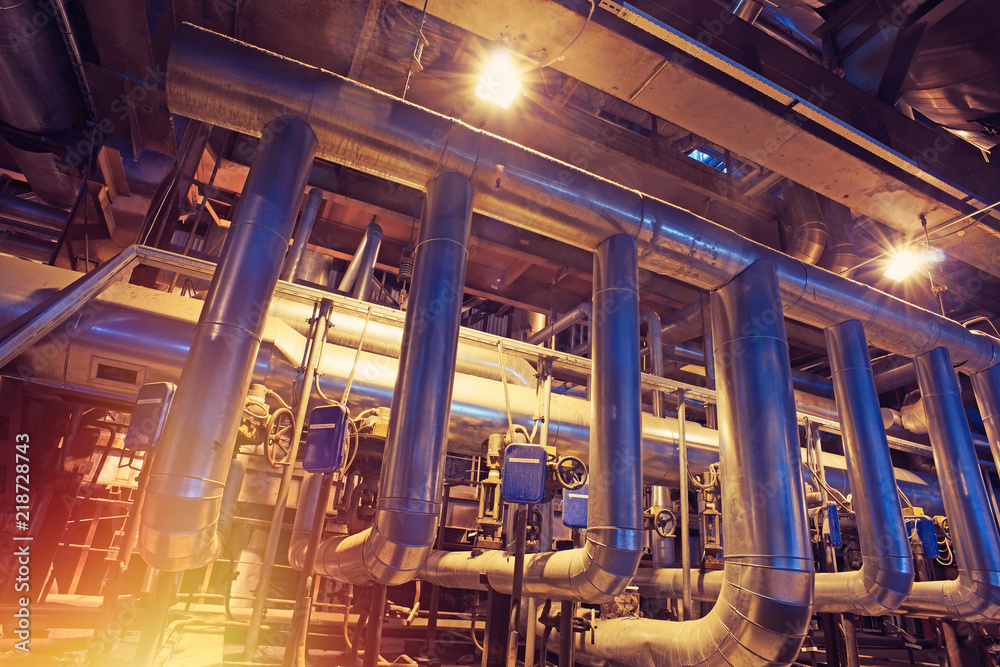 Equipment, cables and piping as found inside of a modern industrial power plant. Industrial zone, Steel pipelines, valves, cables and walkways