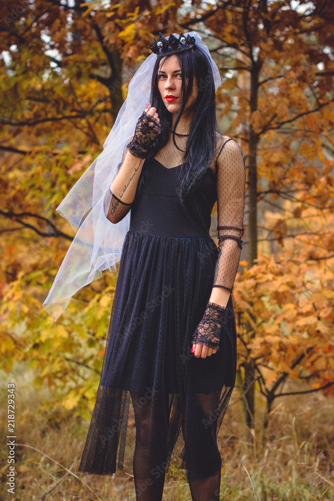 Halloween Witch in a dark forest. Beautiful young woman in witches modern dress . Halloween art design. Dark theme For Halloween Concept 