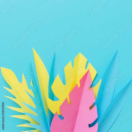 Colorful tropical palm leaves made of paper on blue background. Homemade craft. Summer concept