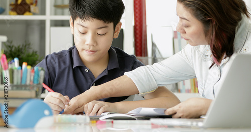 Cute asian mother helping your son doing your homework .