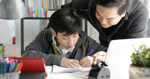 Asian Father and son doing homework at home.